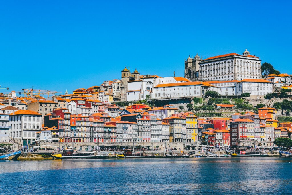 Construções brancas e coloridas perto de corpo de água com embarcações para representar o chip internacional para o Porto. 