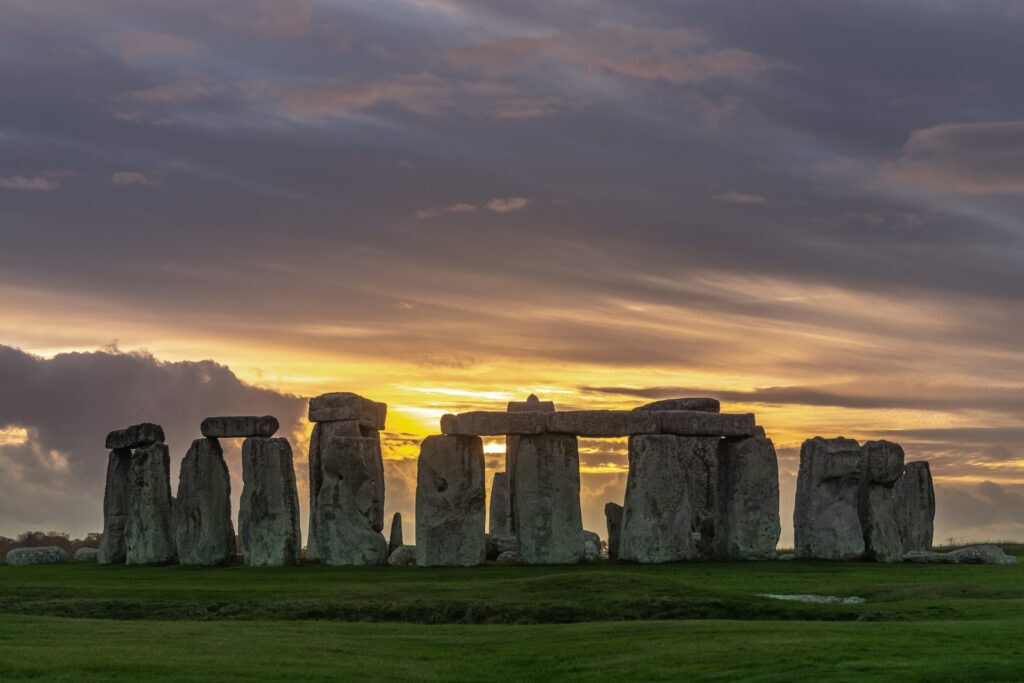 Foto de Stonehenge ao pôr do sol para ilutrar o post sobre chip internacional para o Reino Unido. O monumento é formado por pedras enormes formando um círculo em uma planície esverdeada. - Foto: Jack B via Unsplash