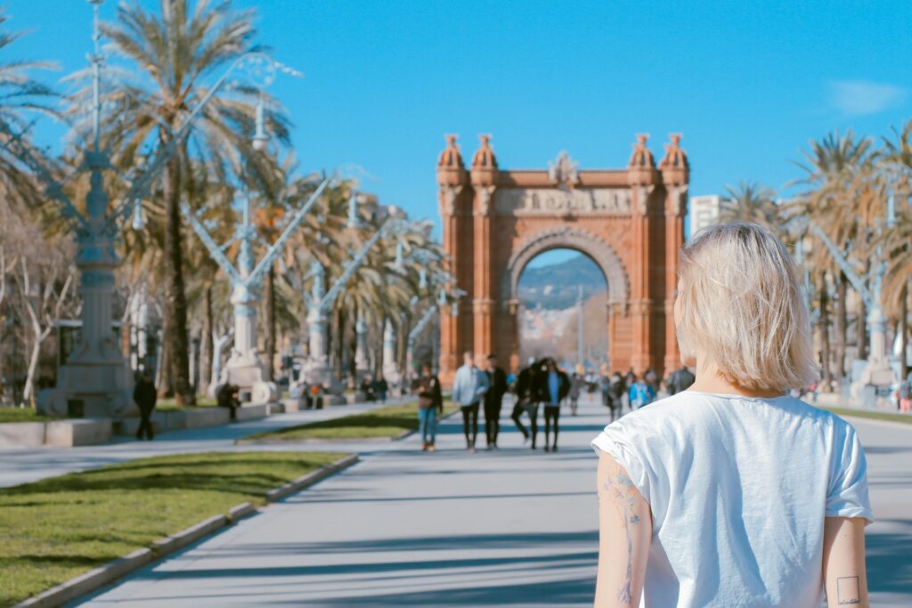 Uma mulher de loira de frente para uma passagem em formato de arco em uma rua de Barcelona na Espanha