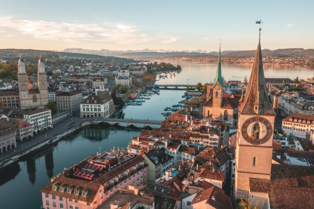 Visão aérea de Zurique para ilustrar o post sobre chip internacional para a Suíça. Casas e catedrais podem ser vistas, e há um rio que corta a cidade ao meio. - Foto: Henrique Ferreira via Unsplash