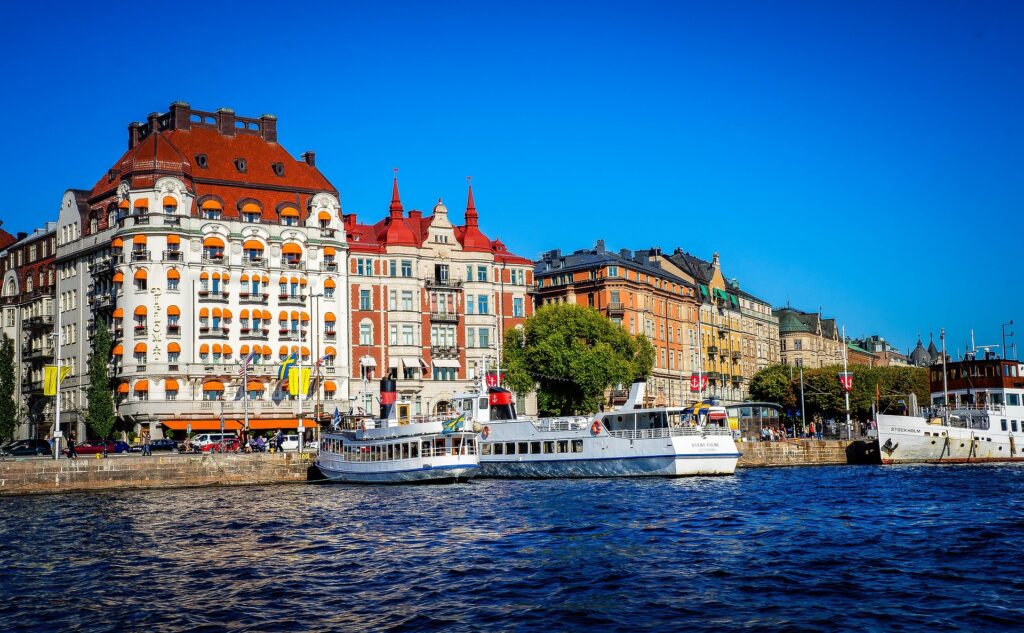 Céu azul e limpo, vários prédios na arquitetura vanguardista de Estocolmo, Suécia. Há um rio em primeiro plano com barcos de turismo. Imagem para representar o chip internacional para Estocolmo