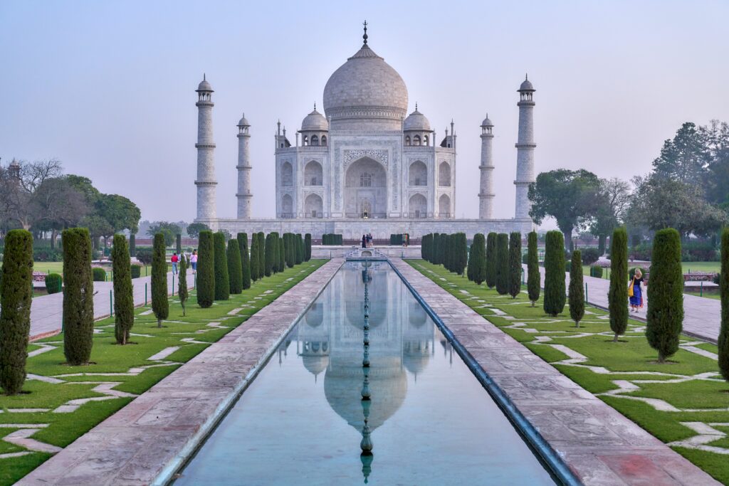 Vista do Taj Mahal durante o dia com uma piscina em frente com árvores em volta e ao fundo o templo. Representa chip internacional para a Índia.