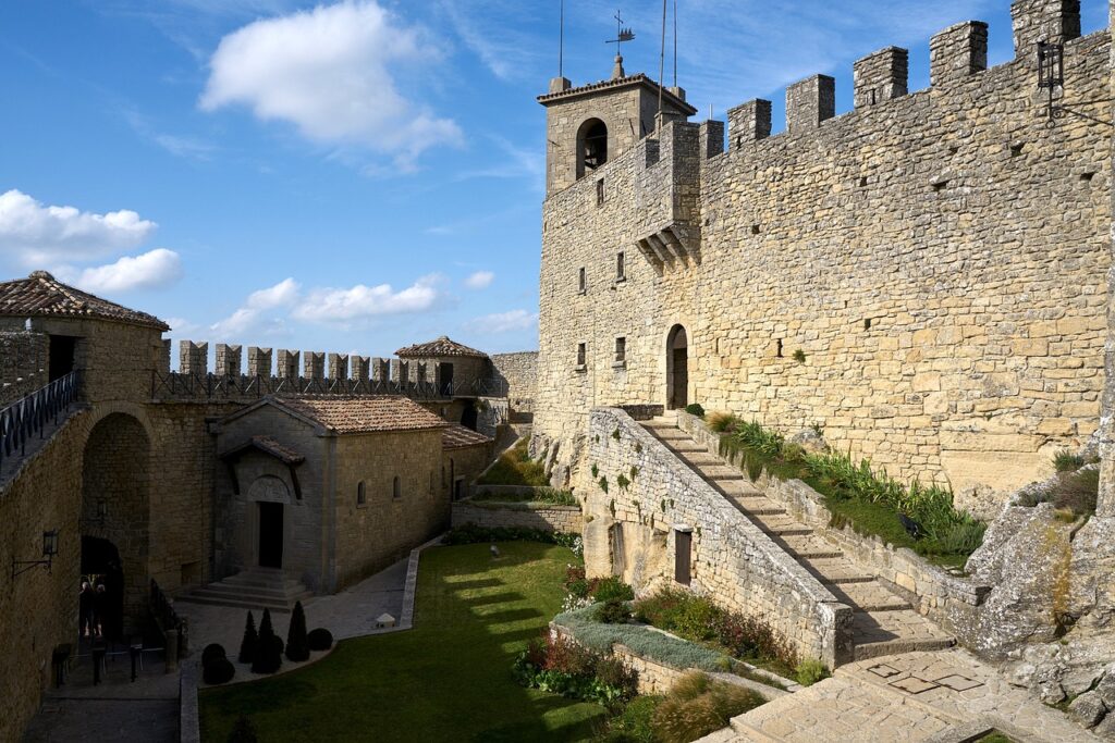 Fortaleza do Castello Della Guaita, em San Marino. Uma escada e uma torre no lado direito, e no meio um jardim.