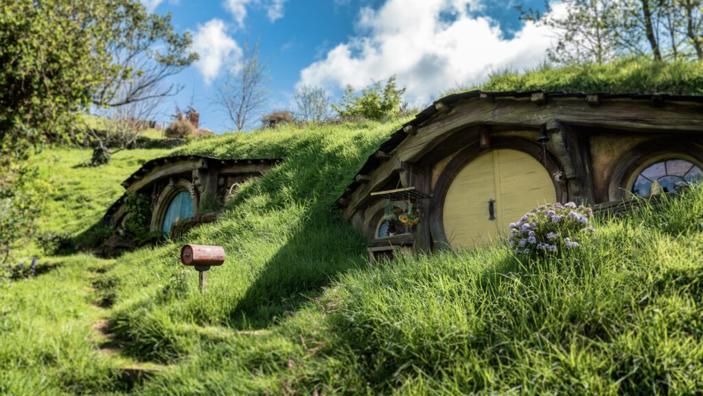 Vista das casas da Hobbiton Movie Set, Nova Zelândia, em volta de vegetação verde durante o dia. 