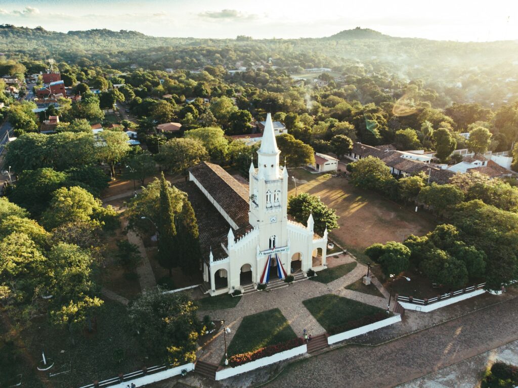 Igreja branca cercada por árvores para ilustrar o post sobre chip internacional para o Paraguai. A foto foi tirada de dia. - Foto: David Ress via Unsplash