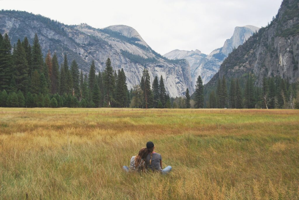 casal sentada na grama em meio à natureza no Parque Yosemite, nos Estados Unidos