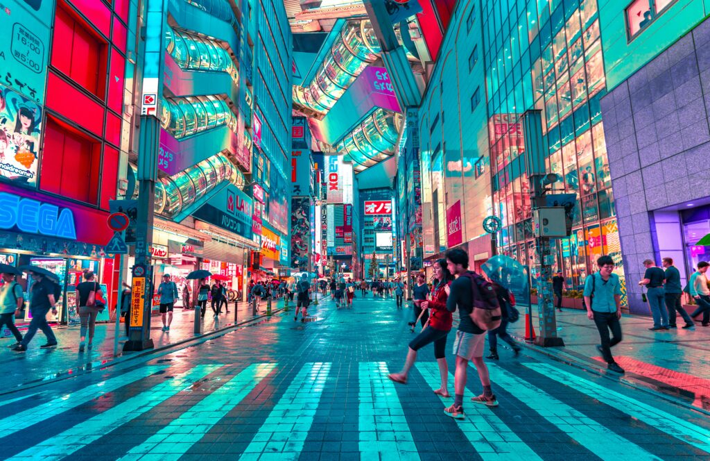Pessoas andando por Tokyo, Japão durante a noite com a cidade bem iluminada.