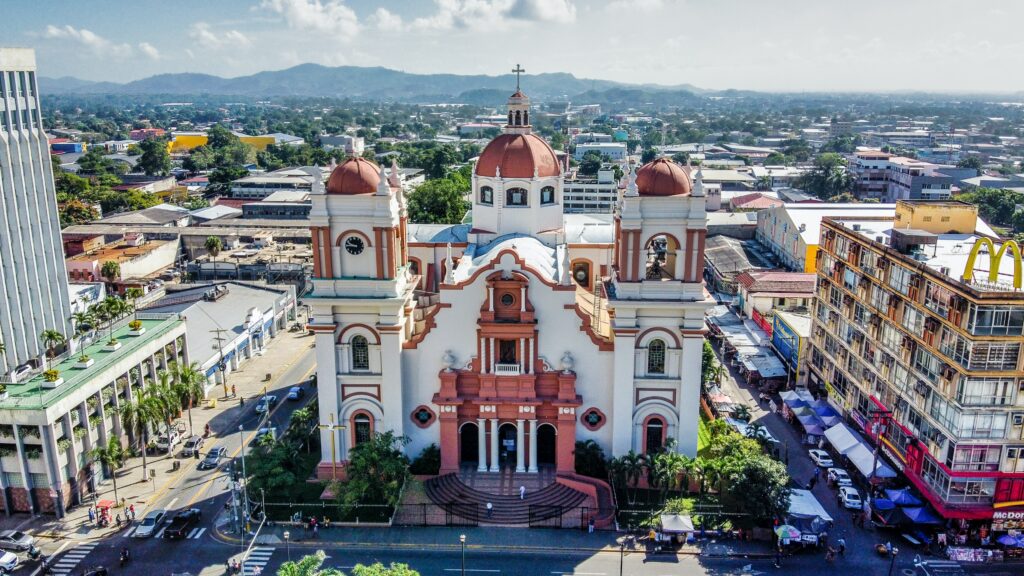Imagem aérea da catedral metropolitana San Pedro Apostol, em Honduras. Ao redor da catedral há vários outros edifícios e casas. Foto para ilustrar o post de chip internacional para Honduras.