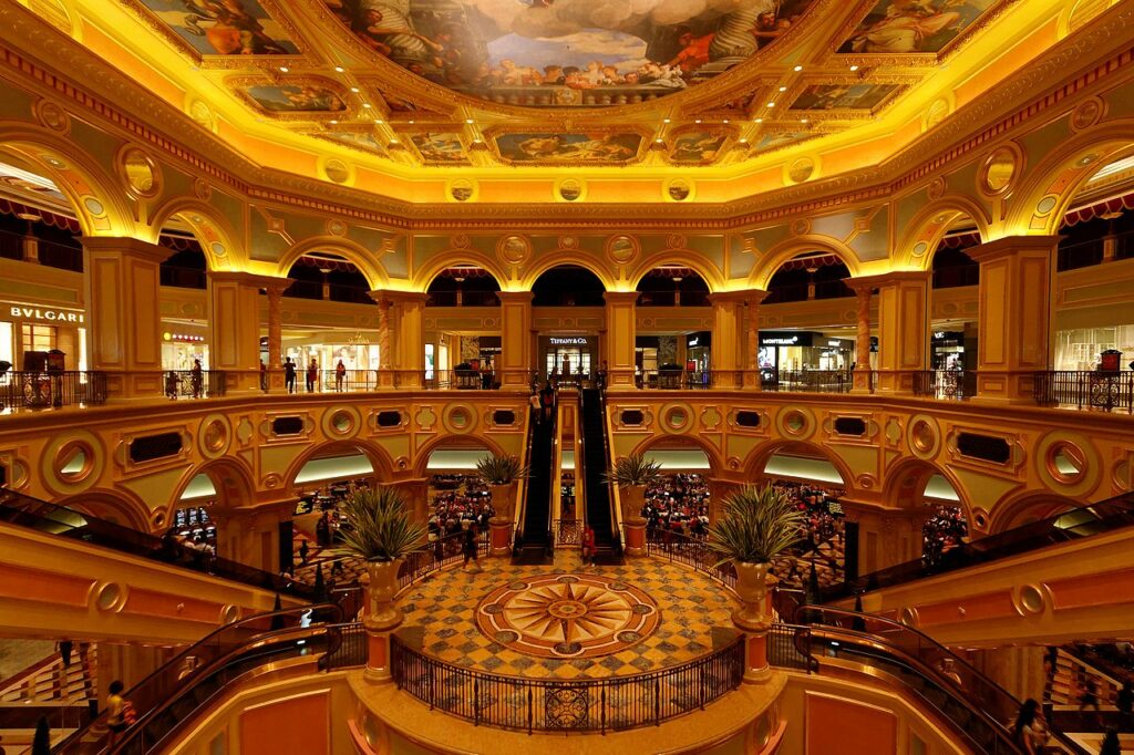 Casino e resort de luxo em Macau. Com mais de um andar, escadas rolantes e muitas pessoas dentro.