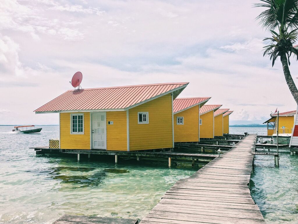 Casas amarelas sobre o mar, em Boca Del Toro, no Panamá. Uma estrada de madeira no meio. Foto para ilustrar post sobre chip internacional para o Panamá.