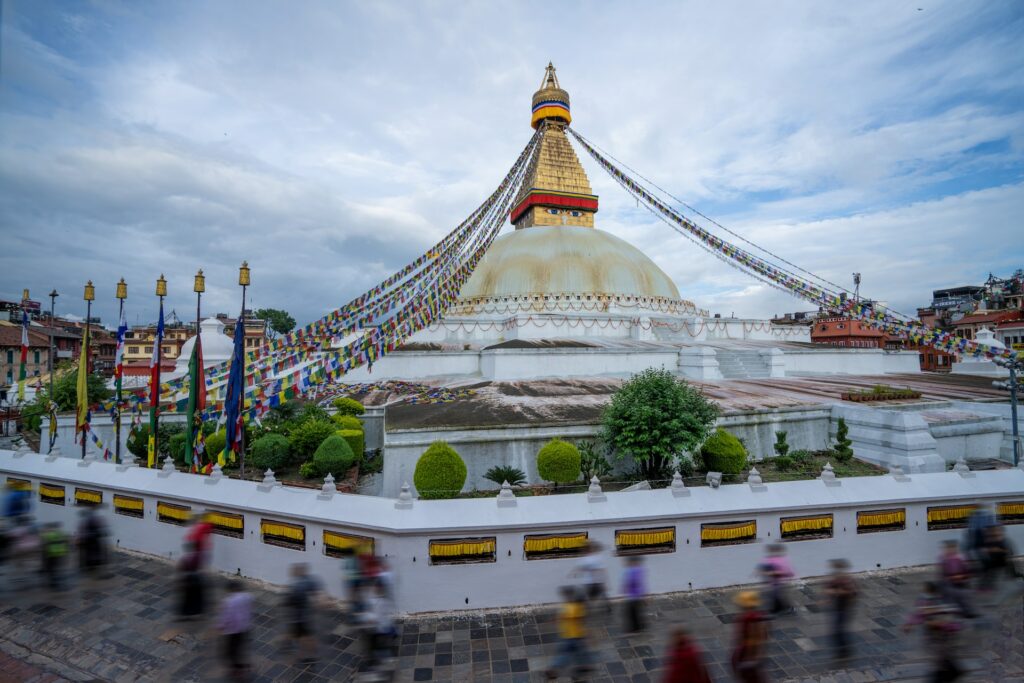 Grande edifício com telhado redondo e uma construção dourada em cima e várias bandeirinhas coloridas durante o dia, ilustrando post chip internacional para o Nepal.