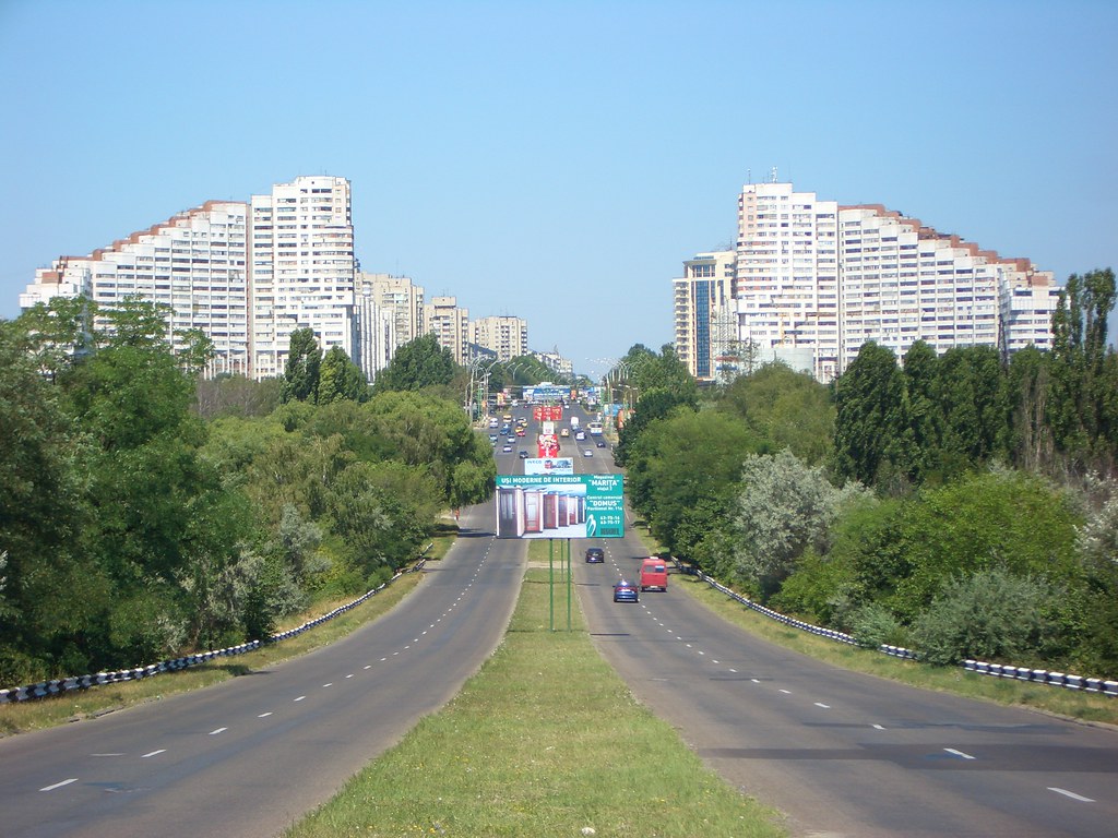 Chisinau, de dia. Duas ruas paralelas, prédios e árvores ao redor. 