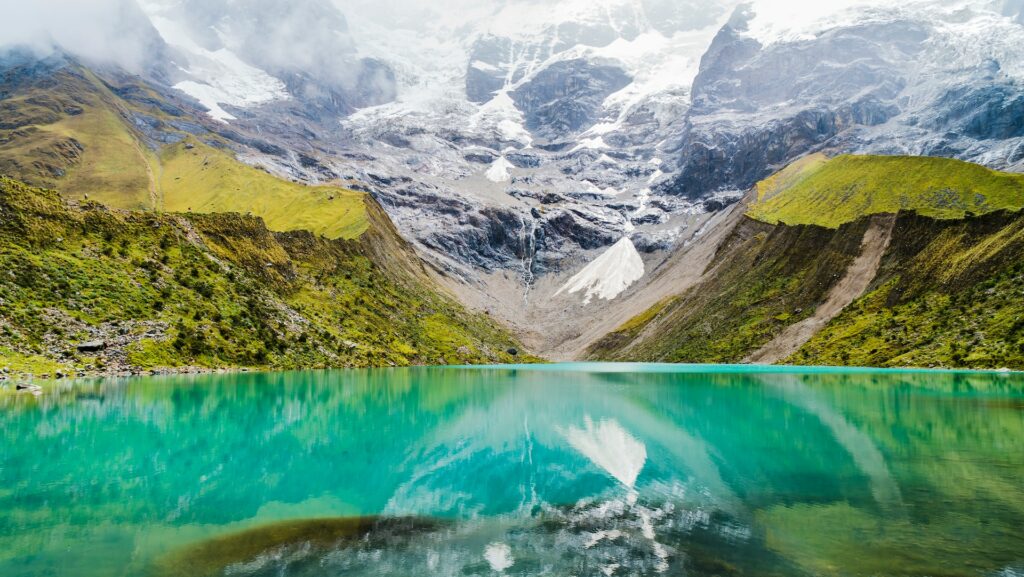 Foto corpo de água com montanhas verdes durante o dia. 