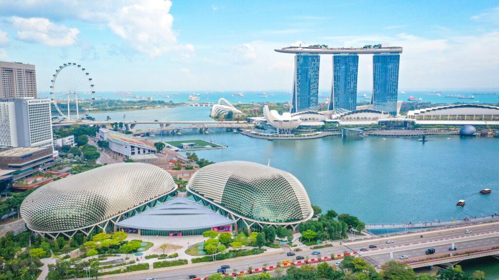 Uma ponte ao centro, construções modernas em volta e corpo da água próximo para representar o chip internacional para Singapura. 