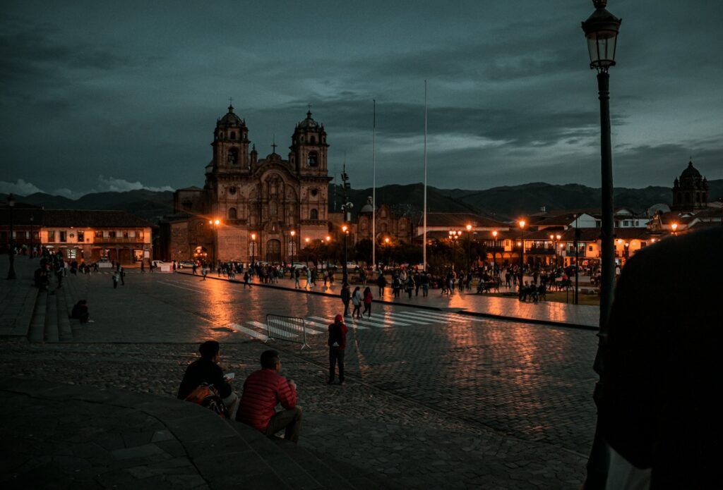 Foto de pessoas andando na rua durante a noite perto de igreja iluminada em Cusco para representar o chip internacional para Cusco. 