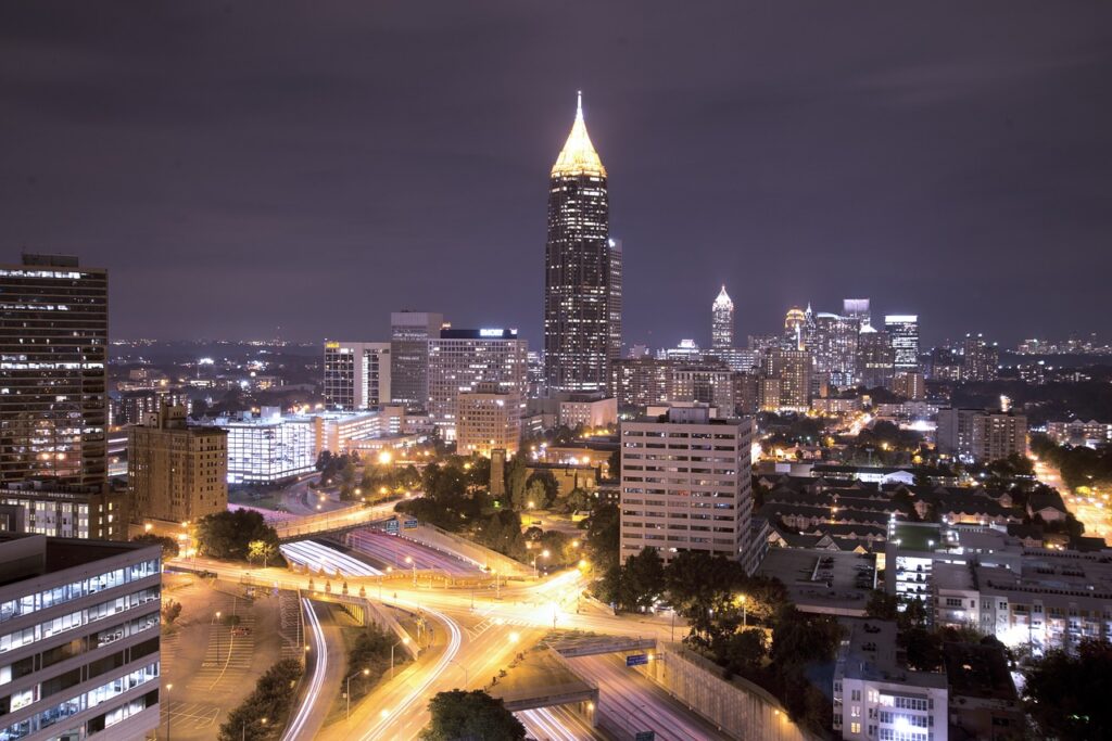 Cidade de Atlanta, na Geórgia. Prédios e ruas todas iluminadas a noite, com ruas paralelas.