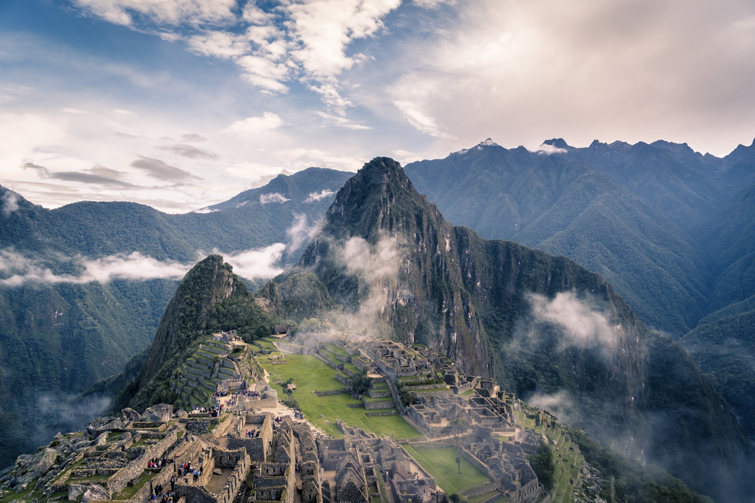 Vista aérea de Machu Picchu com névoa ao redor das ruínas antigas e montanhas verdes sob um céu parcialmente nublado. Representa eSIM Peru.