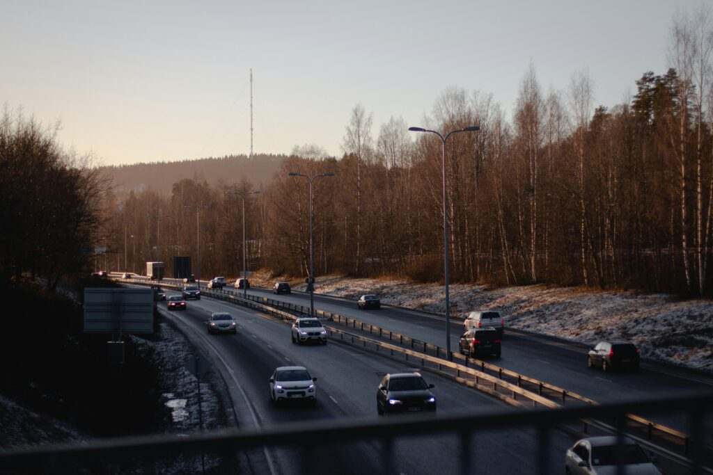 Carros dirigindo em uma rodovia em Jyväskylä, de várias faixas cercada por árvores nuas e uma camada de neve no chão sob um céu nublado. Representa aluguel de carros na Finlândia.