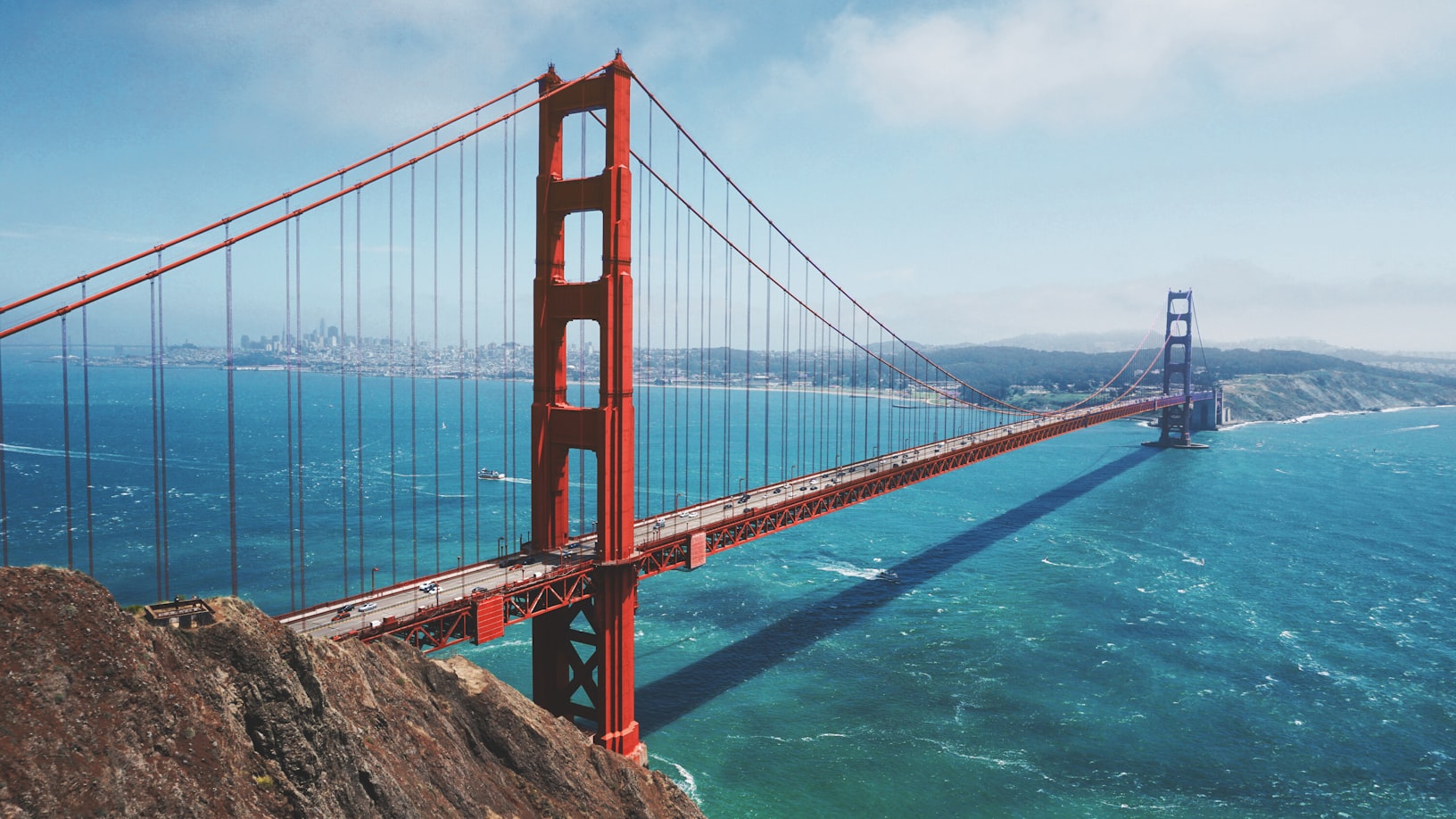 A imagem mostra a Ponte Golden Gate atravessando águas azuis com um céu limpo e o horizonte da cidade ao fundo. Representa eSIM Califórnia.