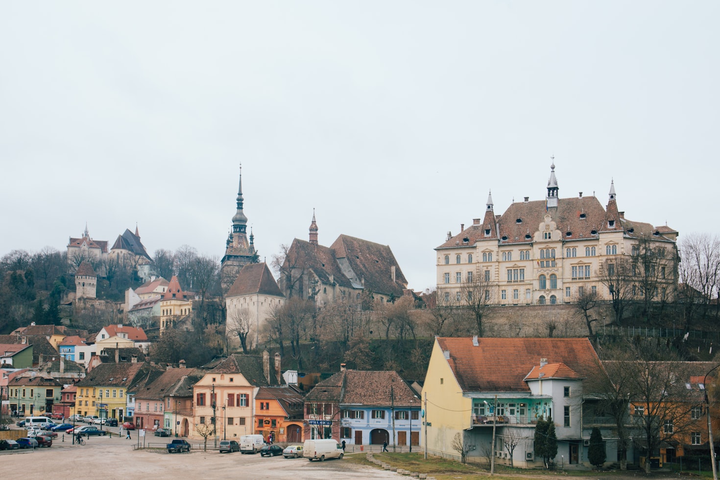 Vista de uma cidade histórica de Sighișoara com um castelo, casas coloridas e uma igreja com uma torre alta em um dia nublado. Representa eSIM Romênia.