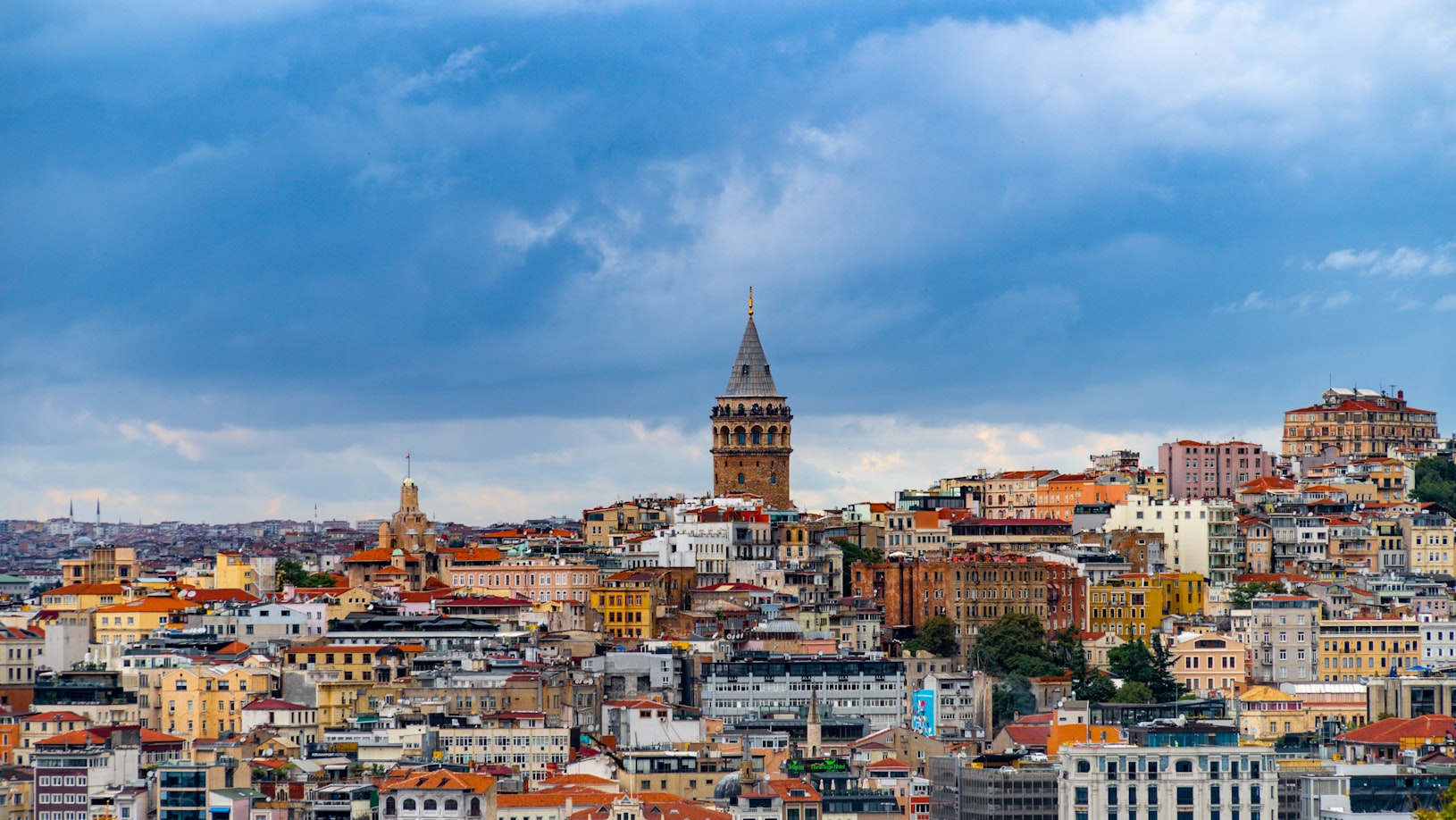 Vista da cidade de Istambul, com a Torre de Gálata, cercada por edifícios coloridos sob um céu parcialmente nublado. Representa eSIM Turquia.