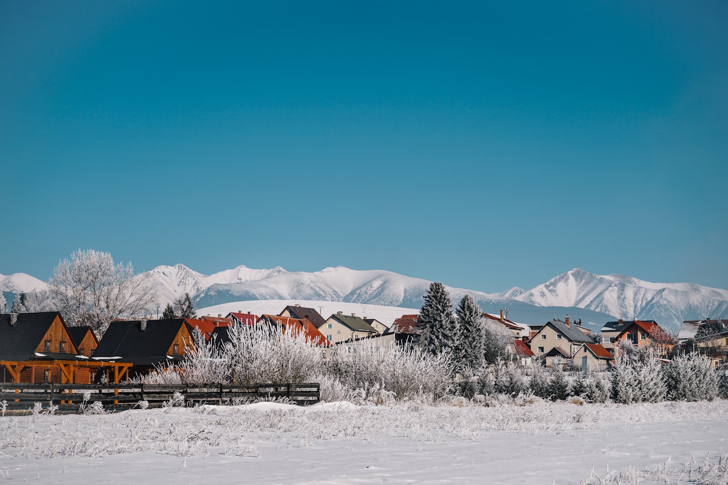 Casas e árvores cobertas de neve em Liptovský Trnovec com uma cadeia de montanhas ao fundo sob um céu azul claro. Representa eSIM Eslováquia.