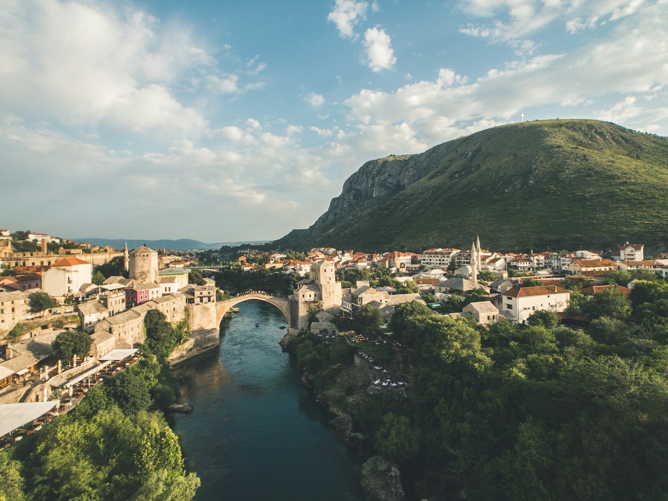 Vista aérea da ponte Stari Most sobre o Rio Neretva em Mostar, cercada por edifícios históricos e paisagens montanhosas. Representa eSIM Bósnia e Herzegovina.