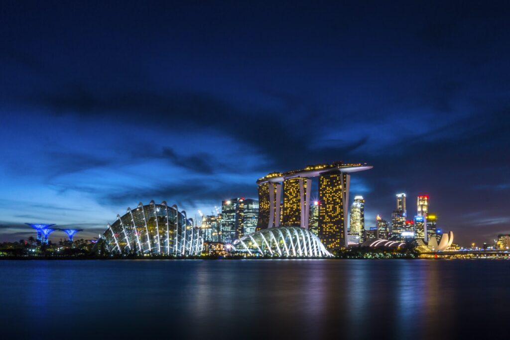 Vista noturna do Marina Bay Sands e edifícios ao redor com luzes da cidade refletidas na água em Cingapura.