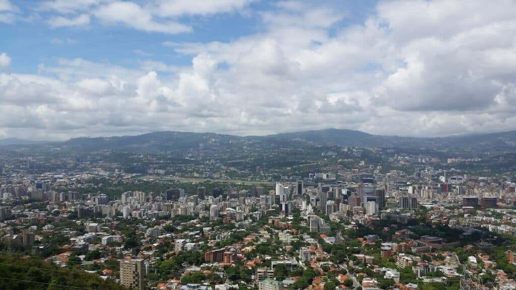 Uma vista da cidade com arranha-céus, vegetação e montanhas ao fundo, sob um céu parcialmente nublado, em Caracas. Representa eSIM Caracas.