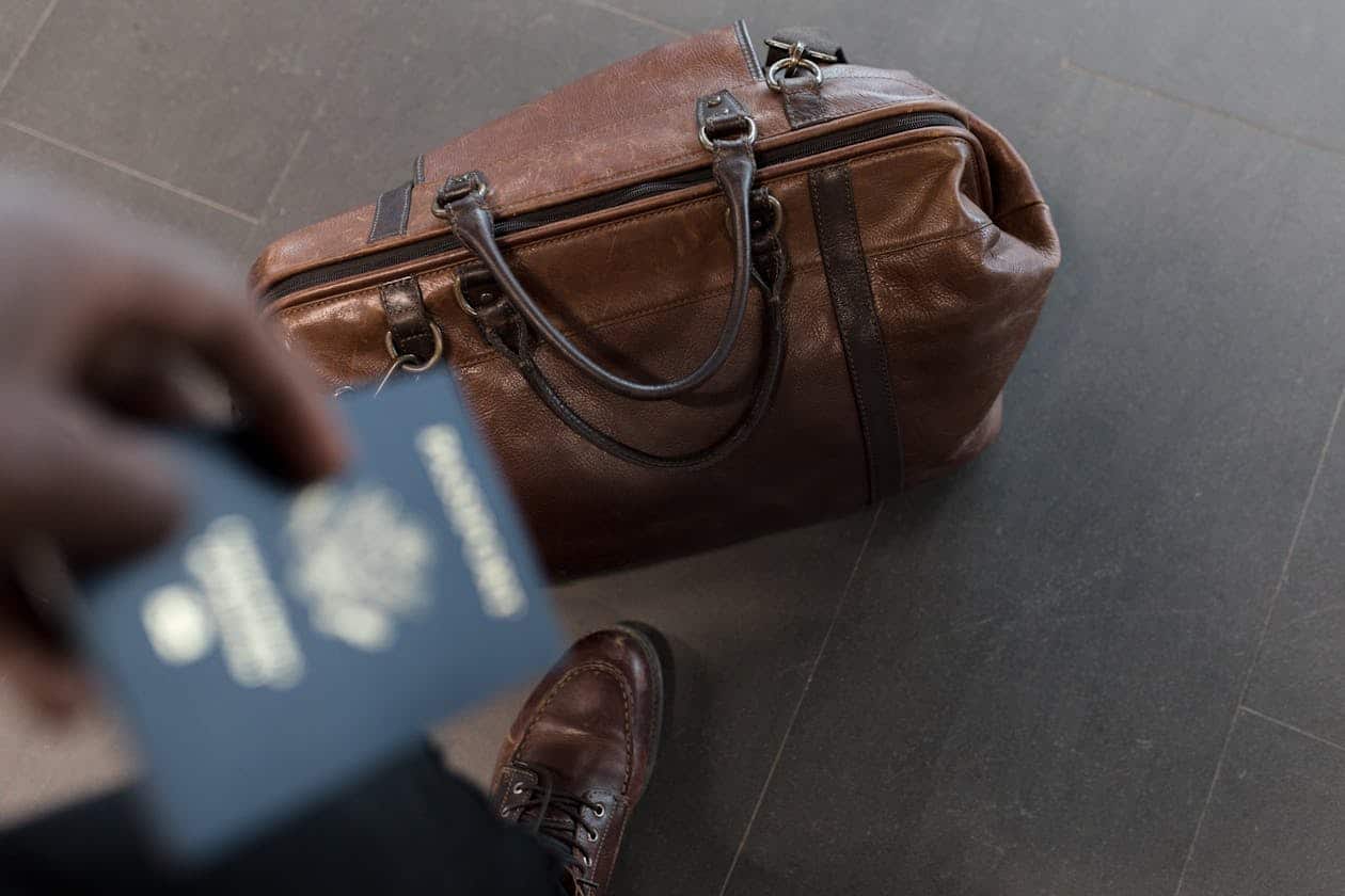Mala de couro com passaporte em aeroporto representando coberturas de seguro viagem como bagagem e documentos