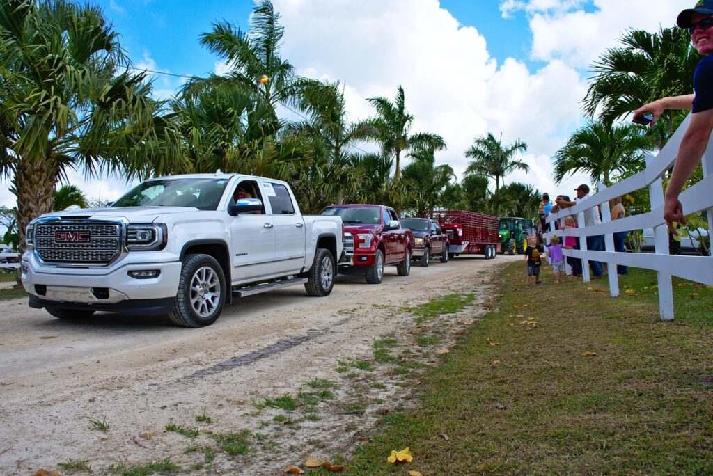 Carros de picape GMC e Chevrolet estacionados em cenário tropical com palmeiras e céu azul com nuvens em Belize, para representar o aluguel de carros