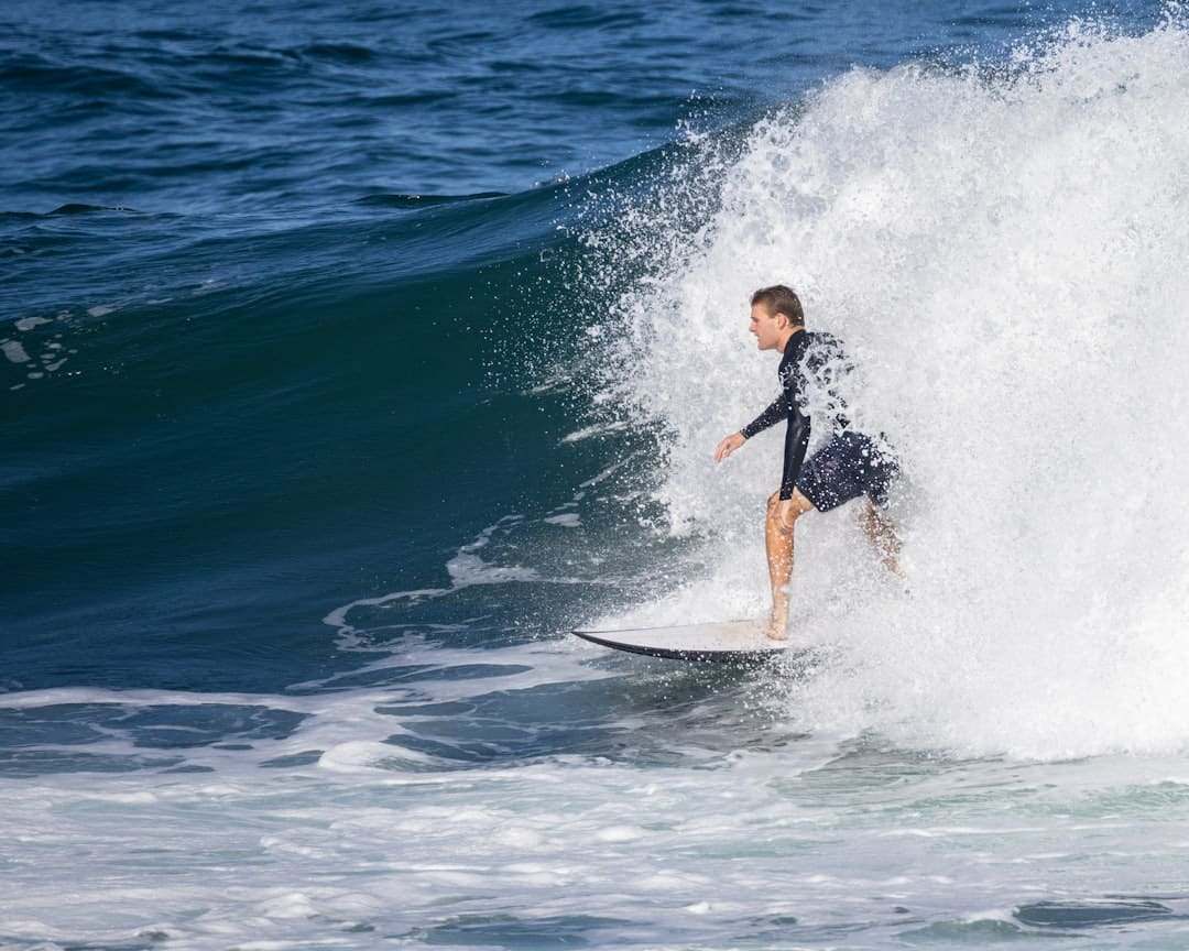 Surfista profissional em onda grande, representando cobertura esportiva do seguro viagem Nest Travel