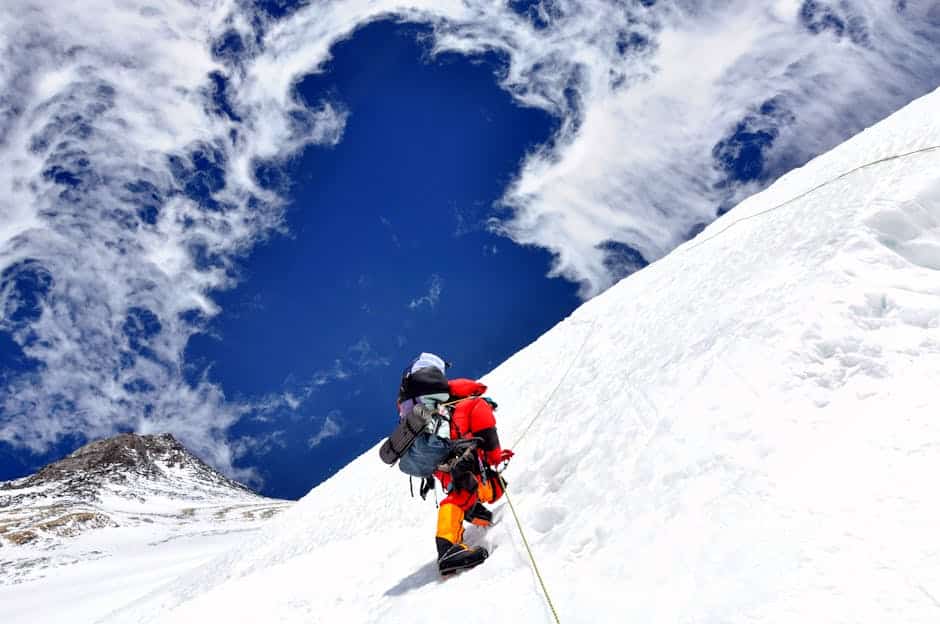 Alpinista exausto descansando em altitude elevada, demonstrando sintomas de mal de altitude