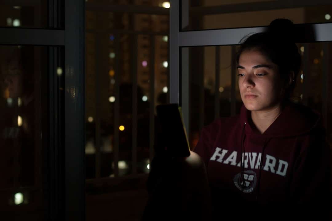 Estudante jovem sozinho olhando pela janela, representando desafios emocionais do intercâmbio como solidão e choque cultural