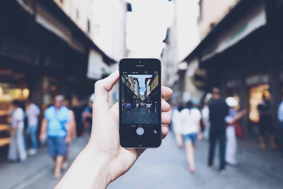 Turista com celular e câmera fotográfica em cidade movimentada, representando risco de roubo de eletrônicos durante viagem